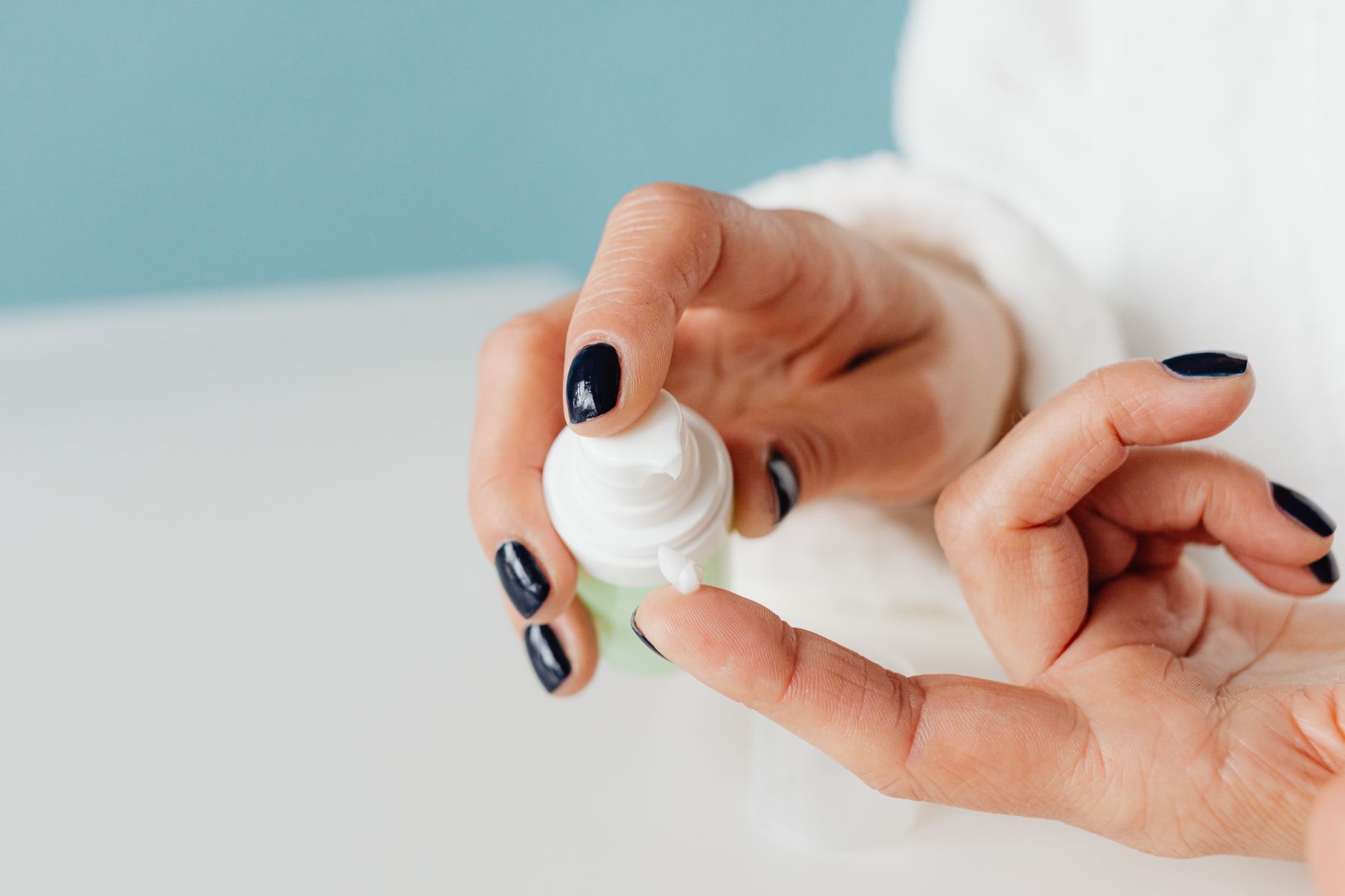 Plan détaillé de mains appliquant une crème de soin avec une mise au point douce.
