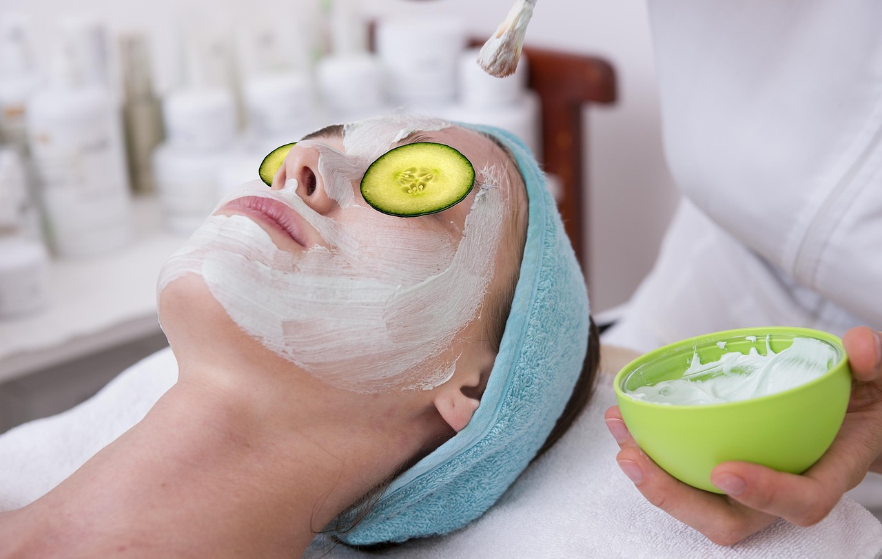 Une femme allongée porte un masque de soin blanc et des rondelles de concombre sur les yeux